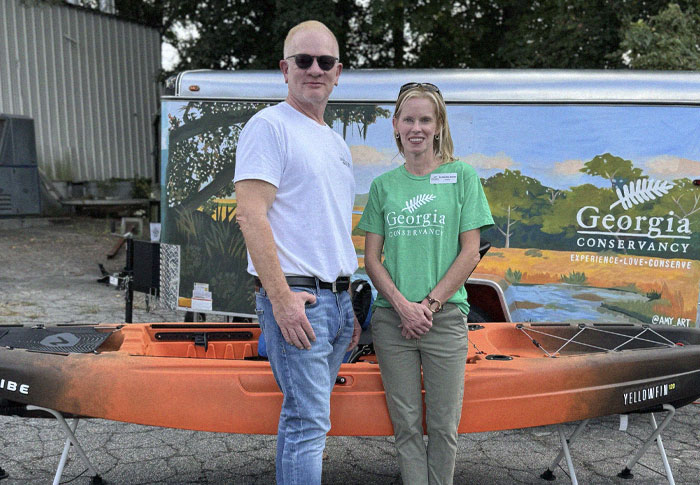 men and woman standing in front of a kayak